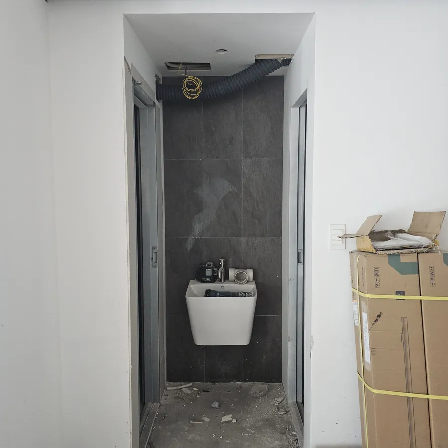 변기가 보이는 타일 공간과 흰색 마감 벽